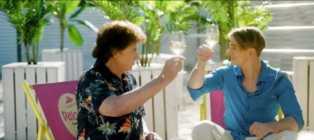 Vincent Gross et Olaf Der Flipper trinquant avec un verre de vin blanc dans une ambiance estivale, dans le clip de leur chanson « Drinking Wine Feeling Fine ».