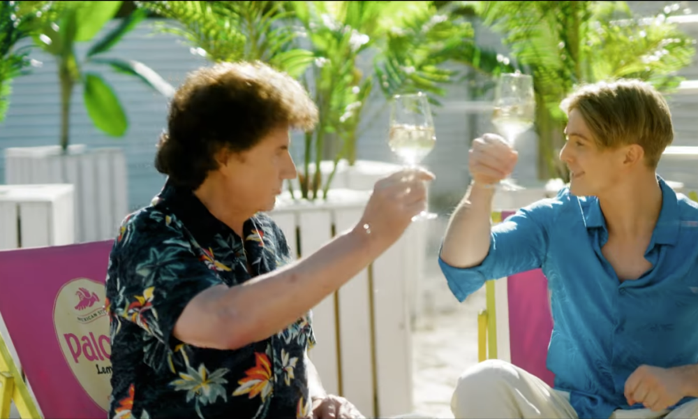 Vincent Gross et Olaf Der Flipper trinquant avec un verre de vin blanc dans une ambiance estivale, dans le clip de leur chanson « Drinking Wine Feeling Fine ».
