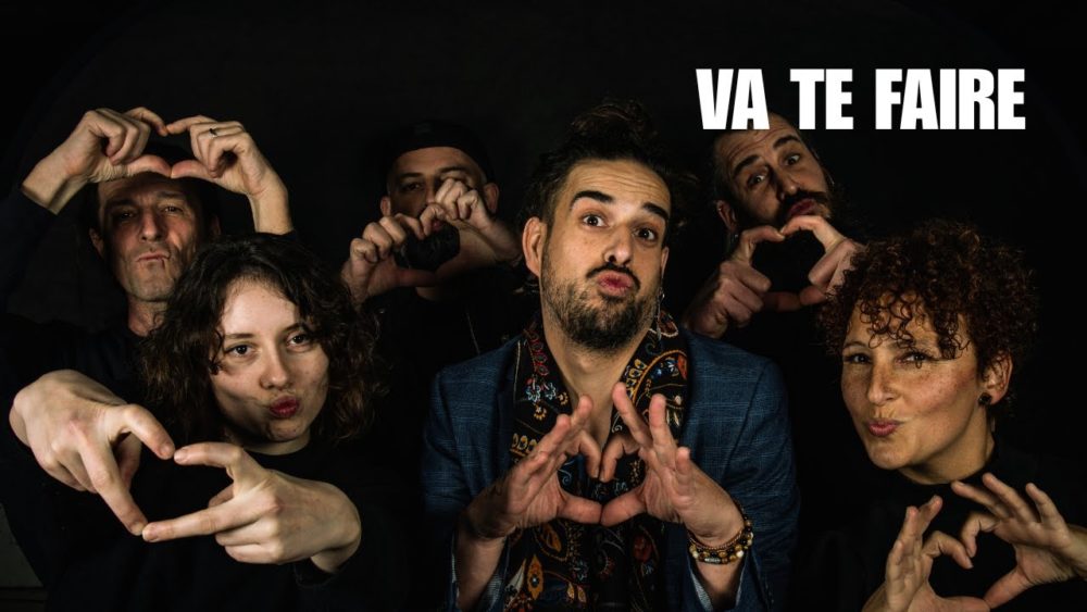 Le chanteur Lozange entouré de plusieurs personnes formant des cœurs avec les mains, dans une ambiance festive issue du clip 