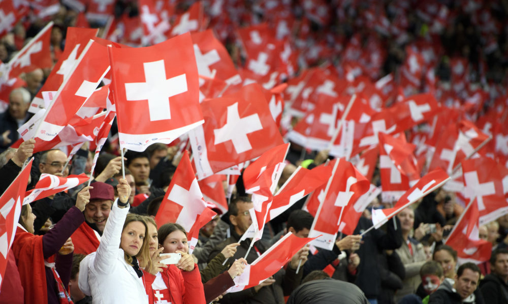 Fans suisses brandissant des drapeaux dans un stade lors d’un match