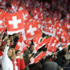 Fans suisses brandissant des drapeaux dans un stade lors d’un match