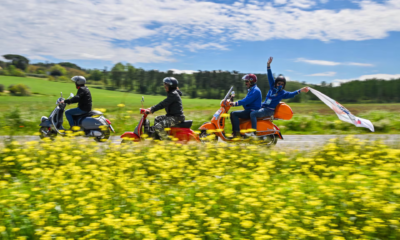 plusieurs scooters vespa roulant dans la campagne pour les 80 ans de la marque