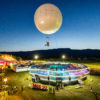 Un artiste suspendu sous le ballon Moon Music au-dessus du public du Paléo Festival.