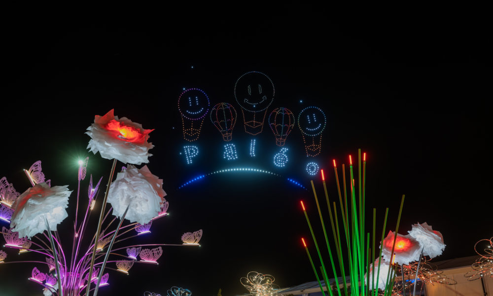 Des drones lumineux forment des montgolfières et le mot Paléo dans le ciel nocturne du festival.